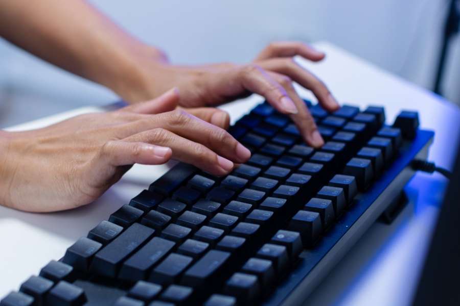 Gros plan sur des mains expertes tapant rapidement sur un clavier mécanique moderne, illustrant la phase active de rédaction de prompts.